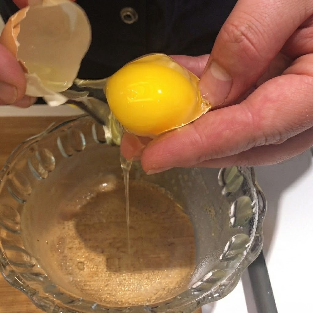 Un jaune dœuf cassé et lâché de sa coquille dans un bol en verre transparent.