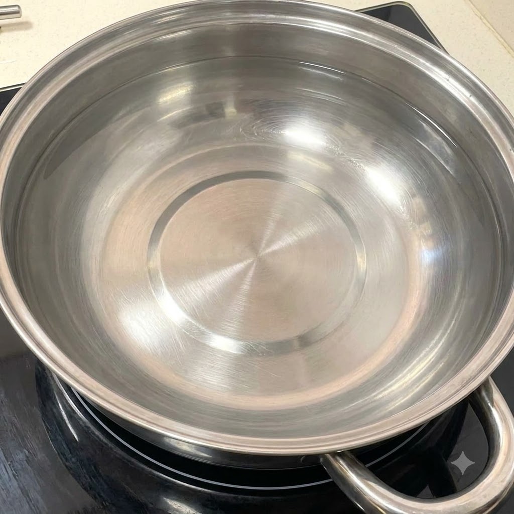 Une casserole propre en acier inoxydable remplie deau sur un feu de cuisson.