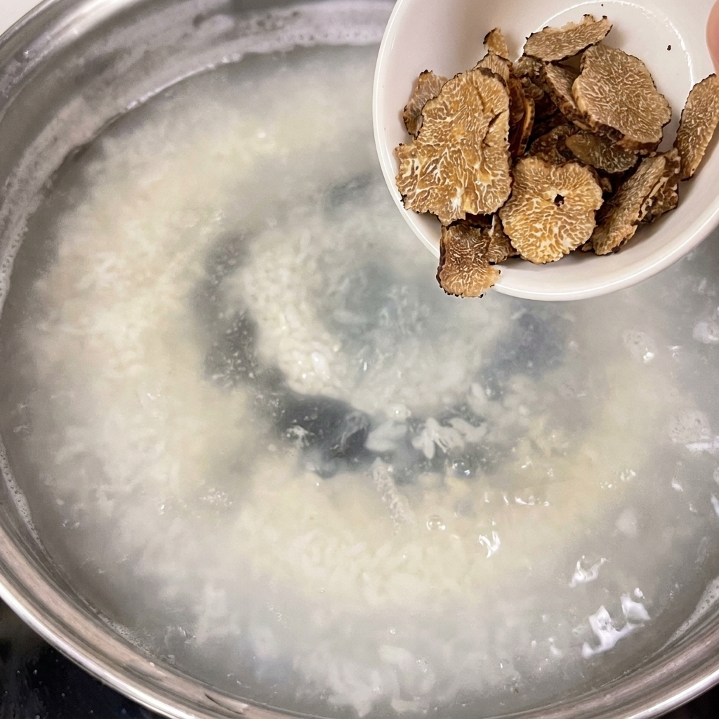 Un petit bol blanc contenant des truffes tranchées versées dans une casserole deau frémissante.