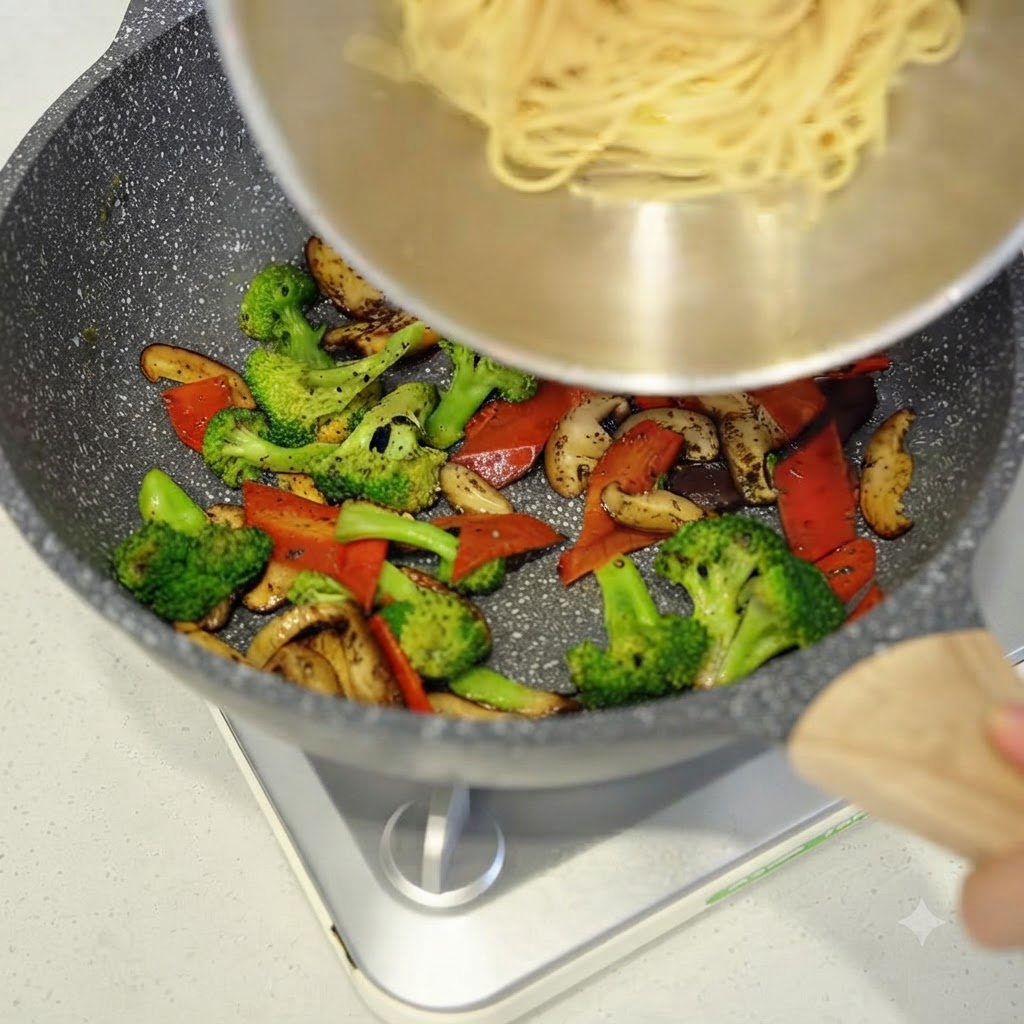 Des spaghettis cuits ajoutés dun bol dans la poêle avec les légumes sautés.