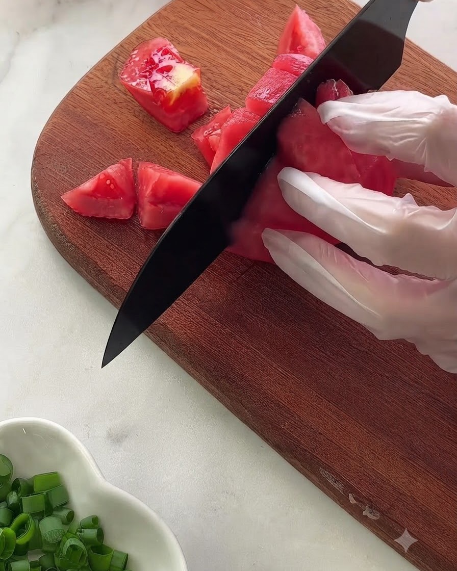 Gros plan sur divers ingrédients et assaisonnements de la sauce mesurés dans un bol en verre posé sur un tissu à pois.