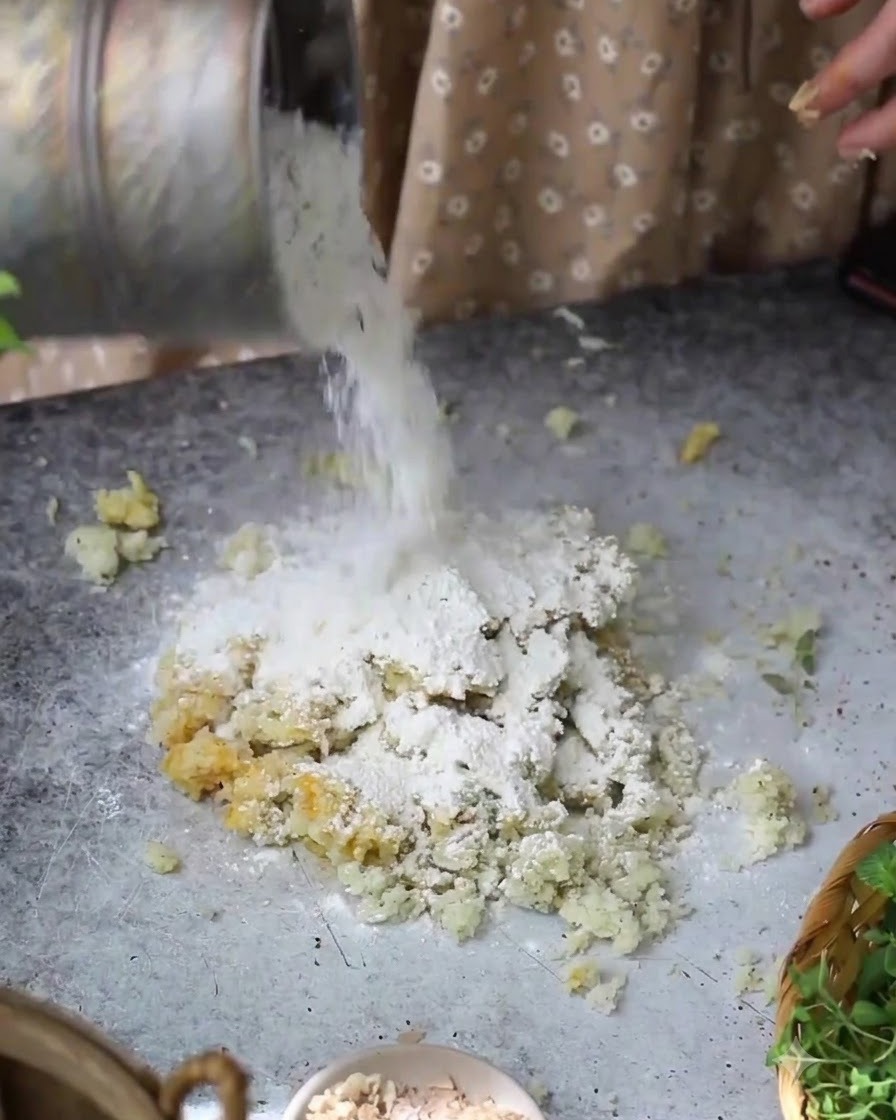 Farine versée dun récipient sur le mélange de pommes de terre et dœufs sur la table.