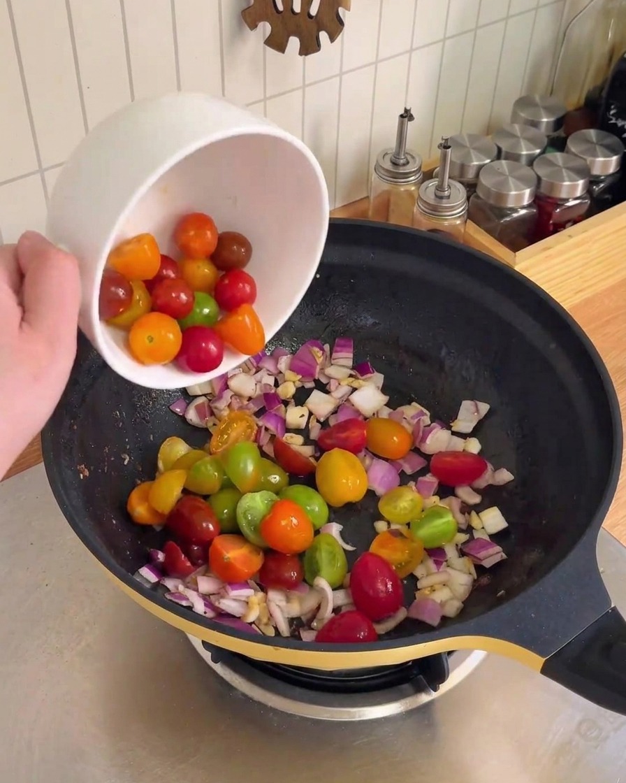 Oignon rouge haché et ail en train dêtre sautés dans un wok noir.