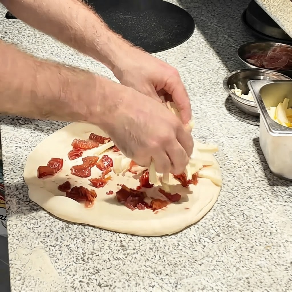 Morceaux de mozzarella parsemés sur la base aux tomates de la pâte à pizza.