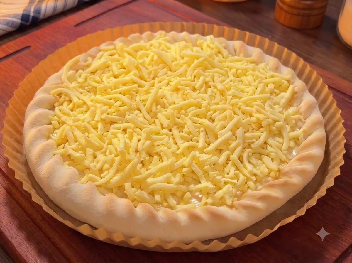 Une base de pizza recouverte de fromage râpé, garnie de morceaux colorés de mangue, de fruit du dragon et de cerises.