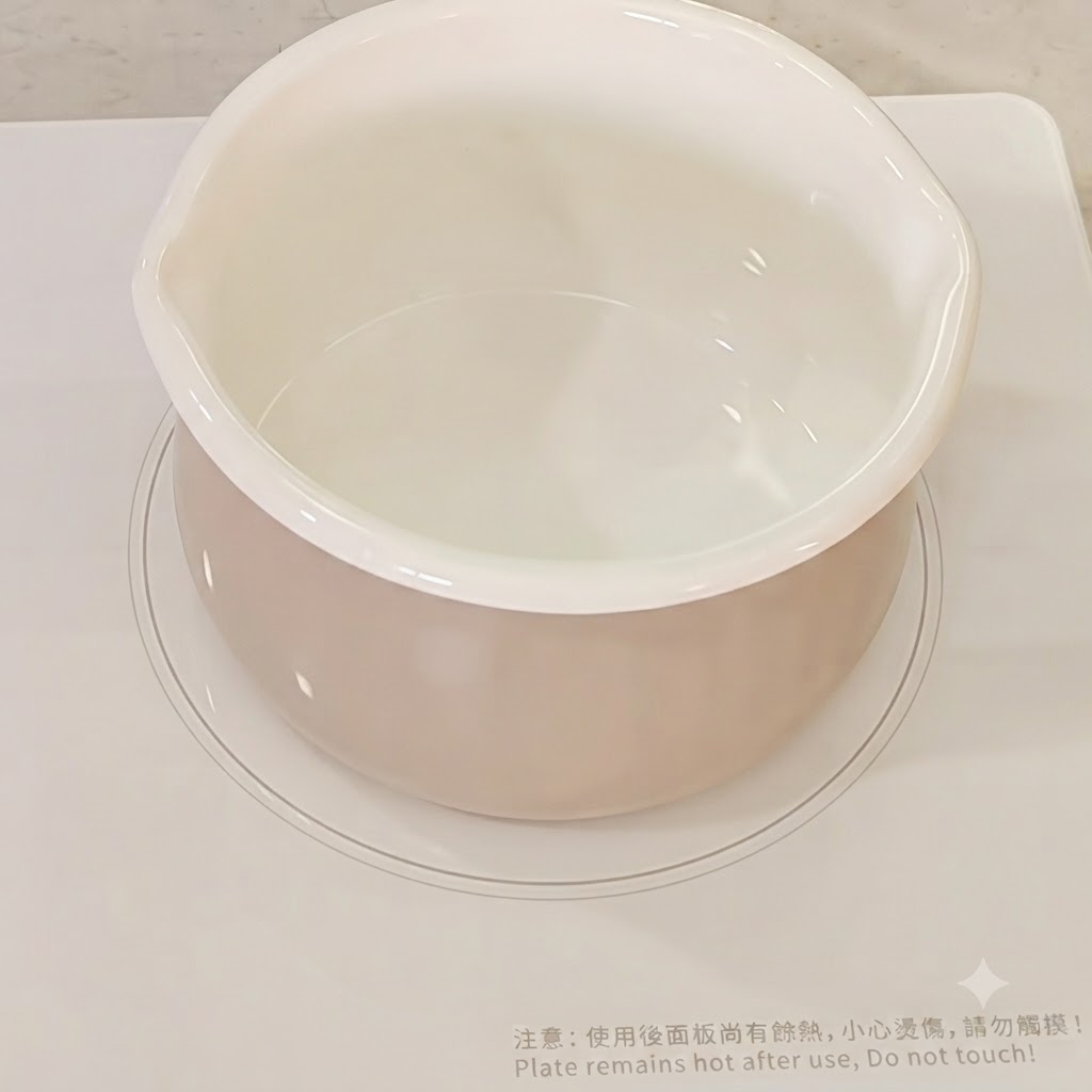 Eau versée dans une casserole blanche sur une cuisinière.