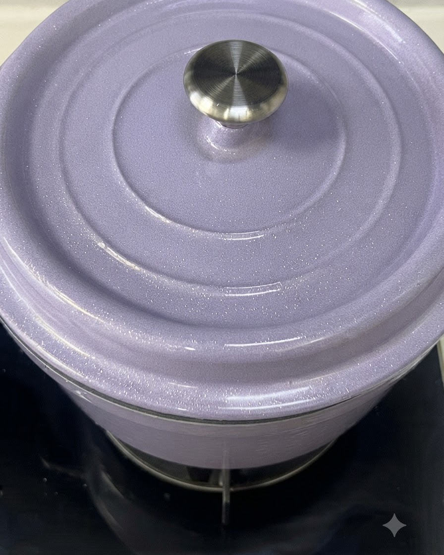 Gros plan sur une cocotte en fonte émaillée violet clair dont le couvercle est en train dêtre posé.