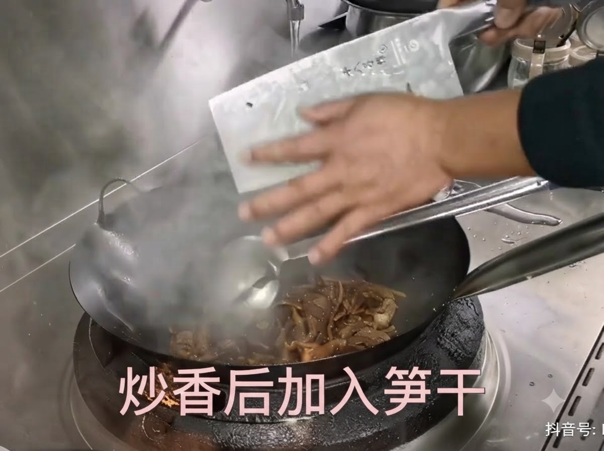 Des pousses de bambou séchées préparées étant raclées dun couteau de boucher dans un wok chaud avec le porc sauté.