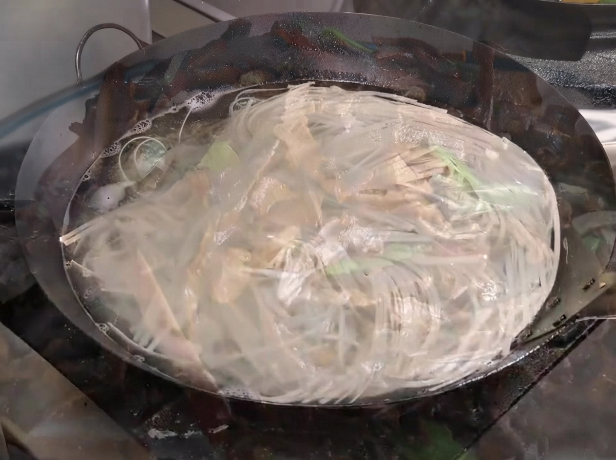 Des nouilles bouillant vigoureusement dans un grand wok rempli deau.
