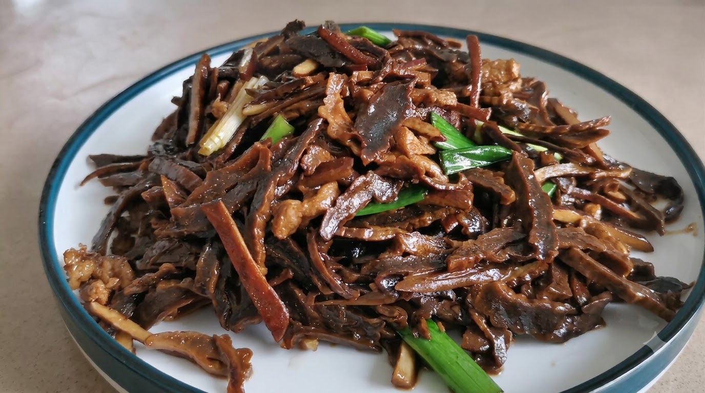 Une assiette de pousses de bambou séchées et de porc émincé sautés et savoureux, garnis de pousses dail vert