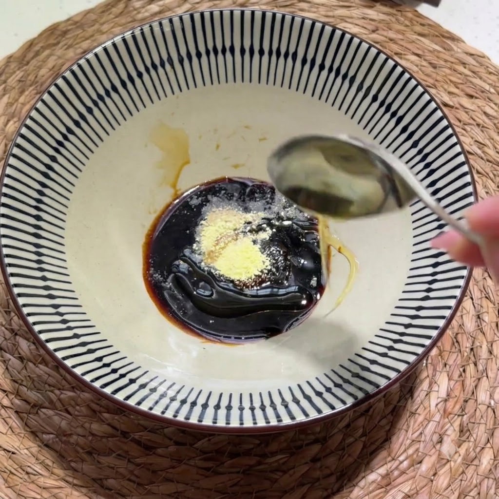 De la pâte épaisse de sésame-cacahuète et un filet dhuile de sésame ajoutés dans le bol dassaisonnements.
