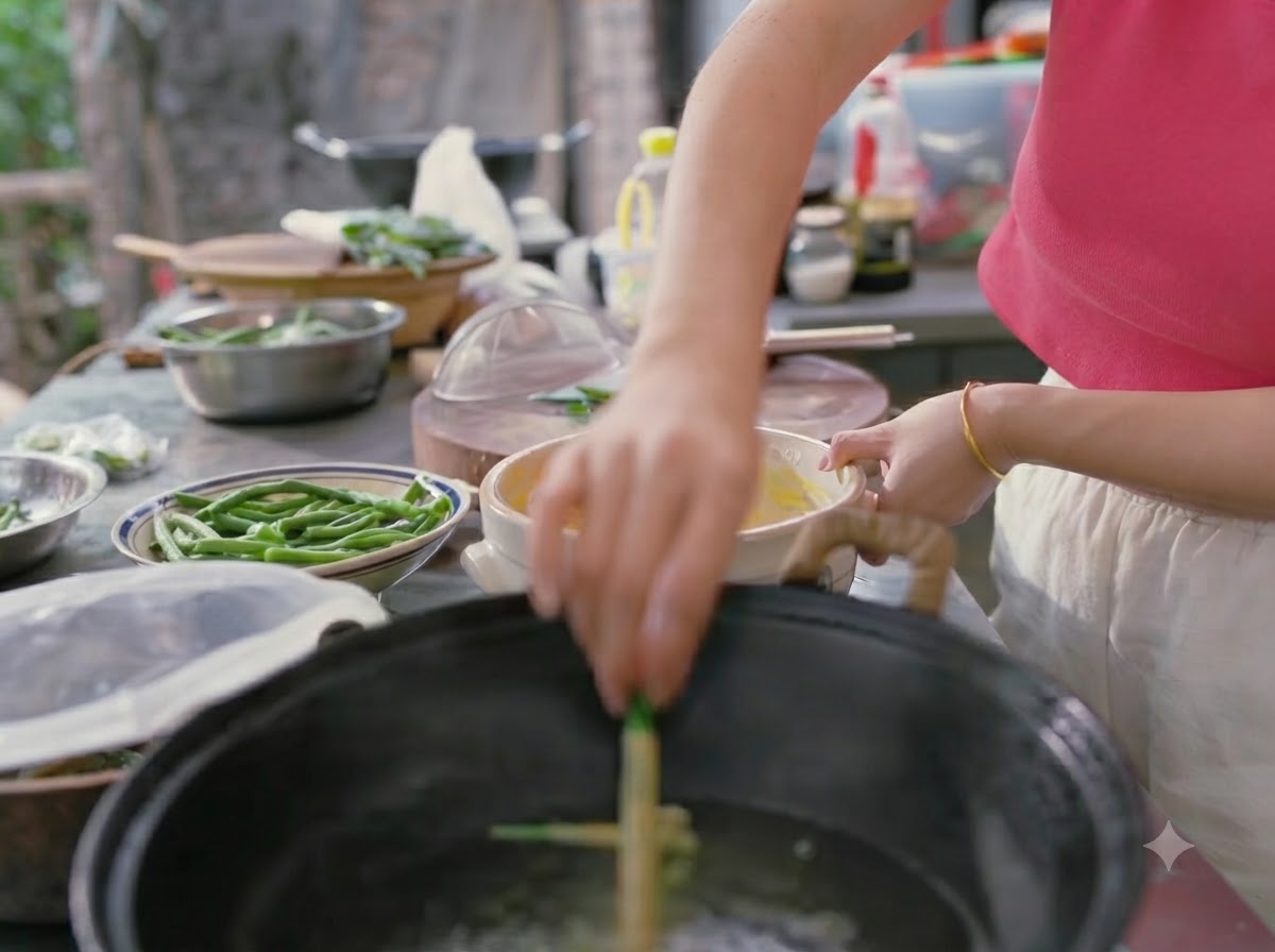 Une main déposant des haricots verts enrobés de pâte dans un wok deau bouillante.