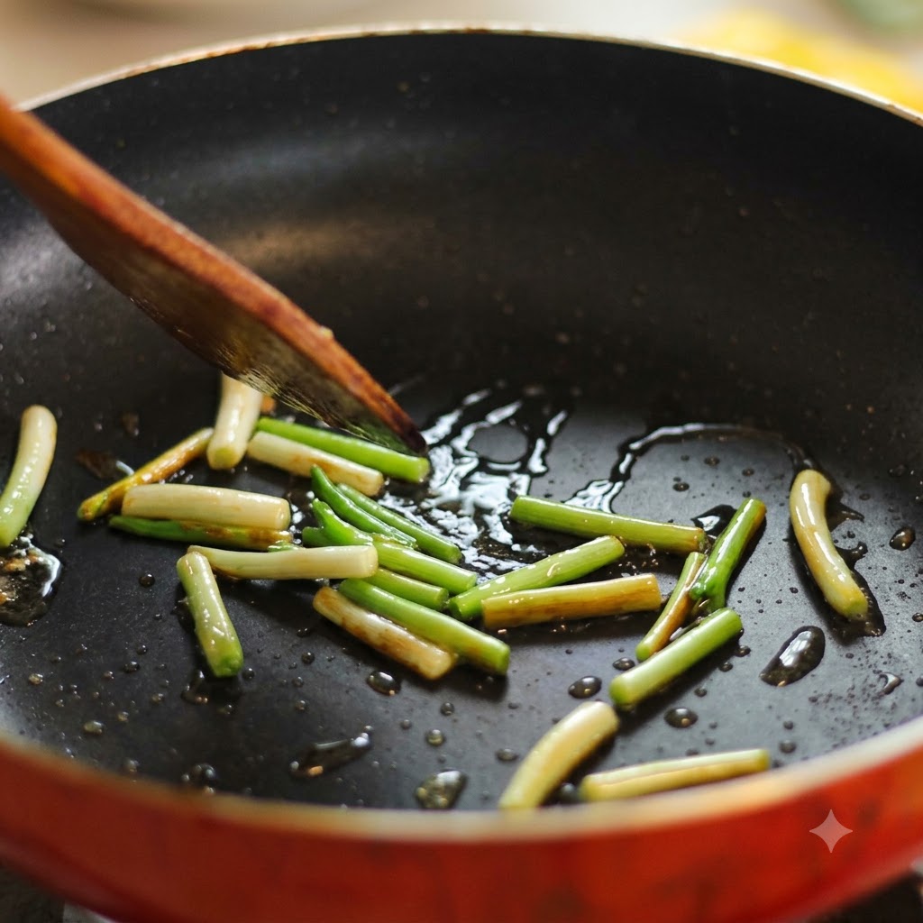 Segments doignons verts grésillant dans une poêle huilée chaude et remués avec une spatule en bois.
