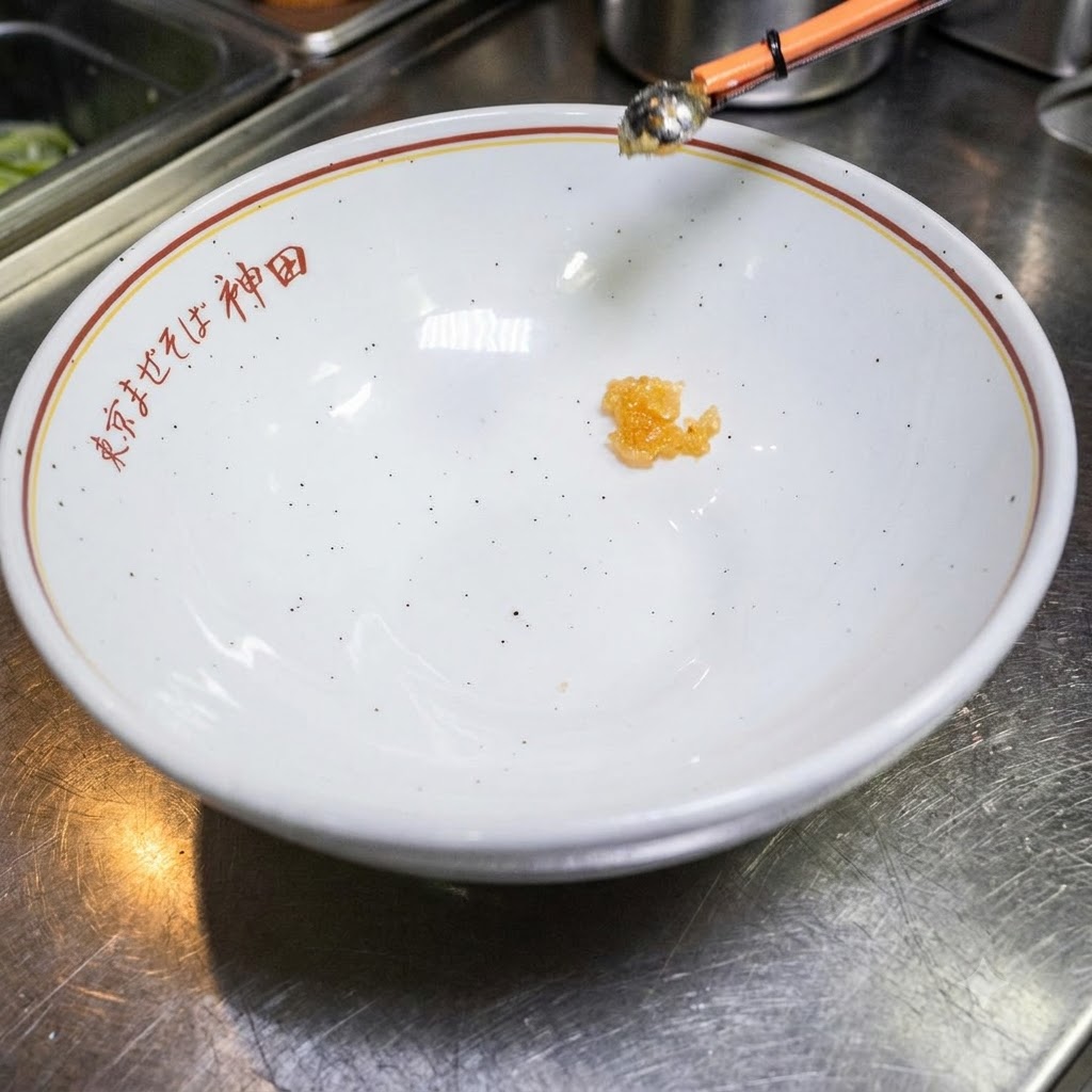Une petite quantité de liquide dassaisonnement au fond dun bol blanc vide avec du texte japonais.