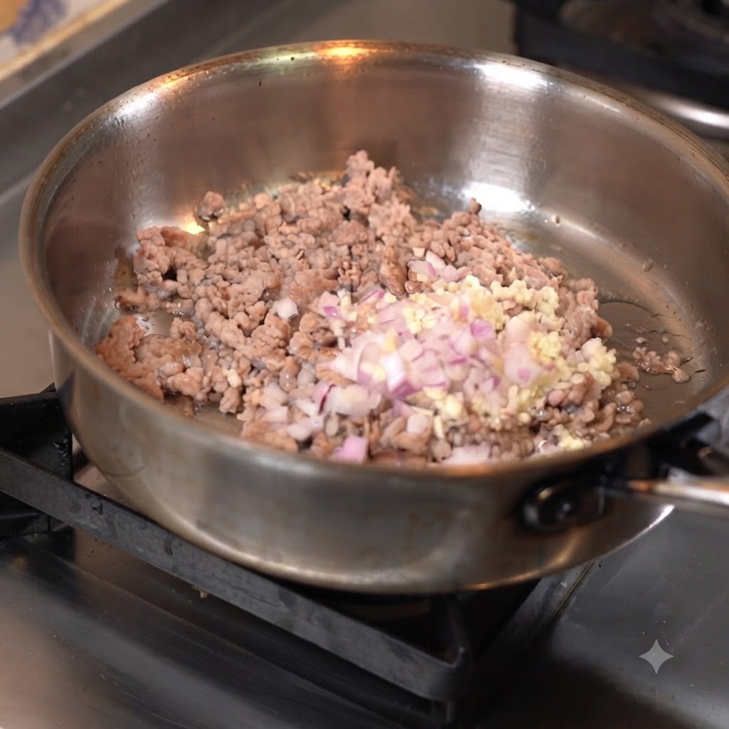 Viande hachée sautée dans une poêle avec de lail et des oignons hachés.
