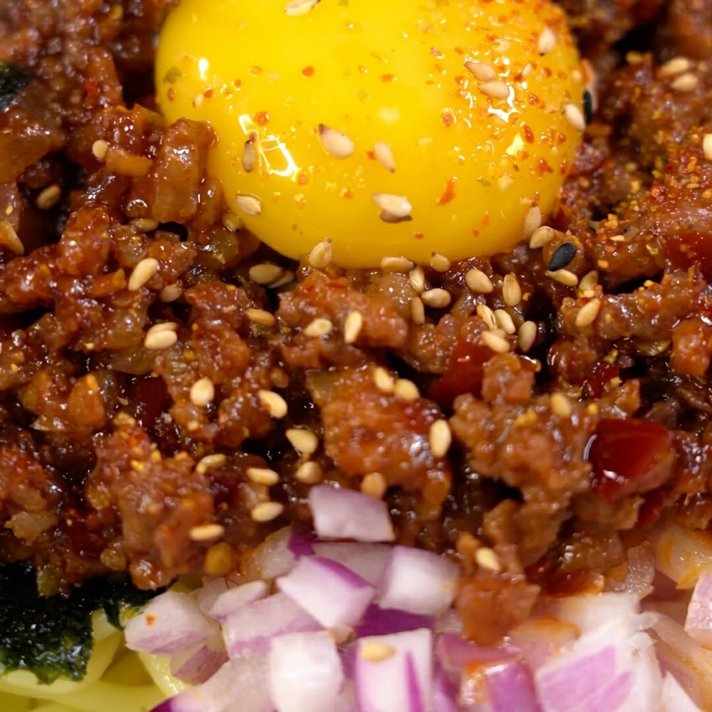 Sauce versée et incorporée à la viande hachée dorée dans une poêle.