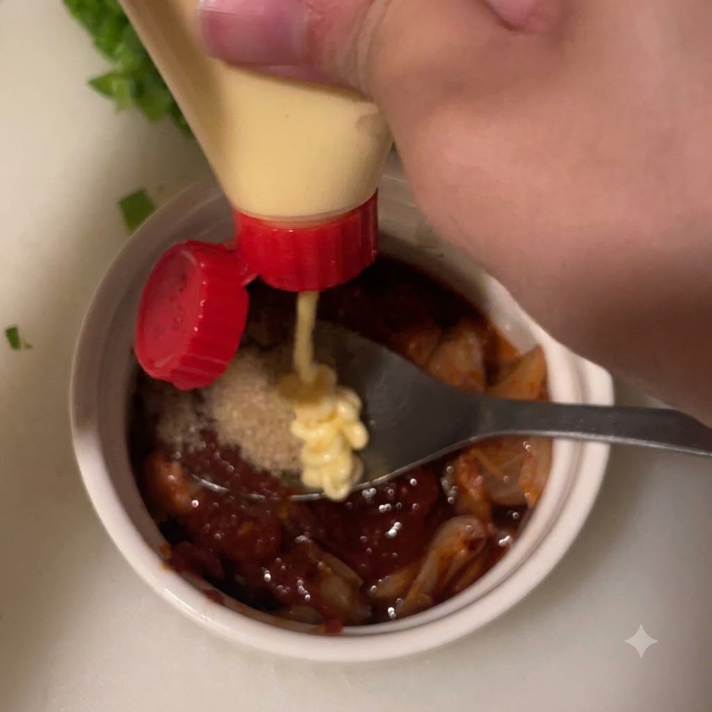 De la mayonnaise pressée à partir dun flacon sur le mélange de sauce dans un petit bol blanc.