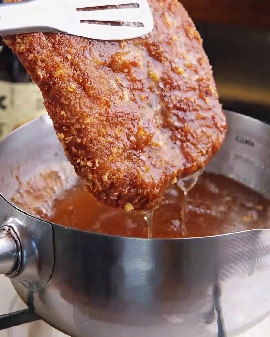 Une côtelette de porc frite dorée et croustillante soulevée de lhuile de friture chaude avec des pinces.