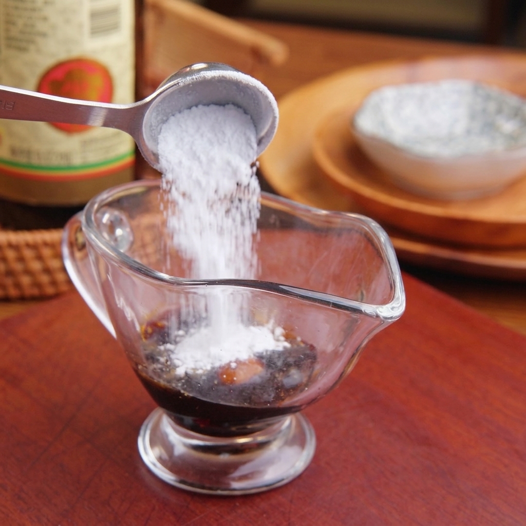 Ajout de sucre et dassaisonnements liquides dans un verre mesureur transparent rempli de sauce soja foncée.