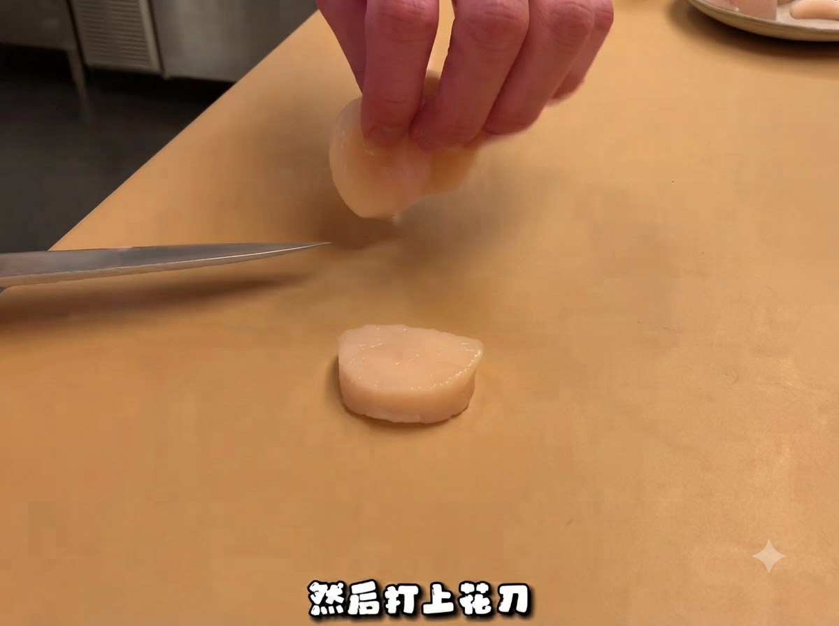 Un couteau de chef près dune noix de Saint-Jacques crue tranchée sur une planche à découper, avec des mains manipulant le morceau.