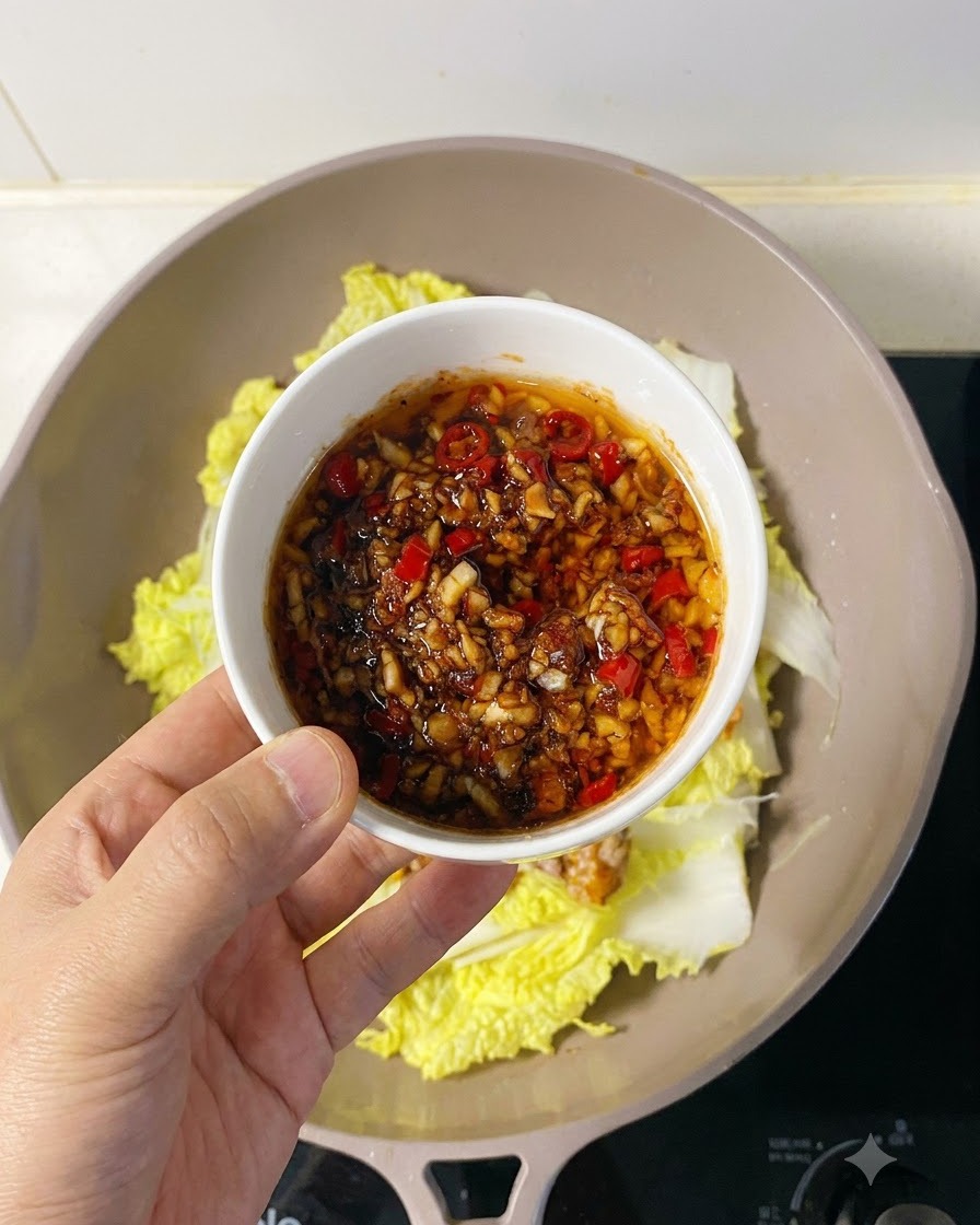 Sauce savoureuse à lail et au piment versée généreusement à la cuillère sur la chair de Saint-Jacques disposée.