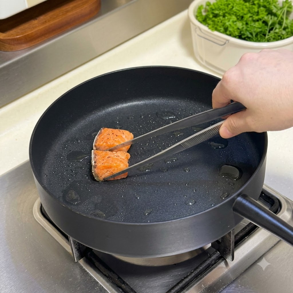 Des cubes de saumon assaisonnés retournés dans une poêle chaude avec une pince de cuisine.