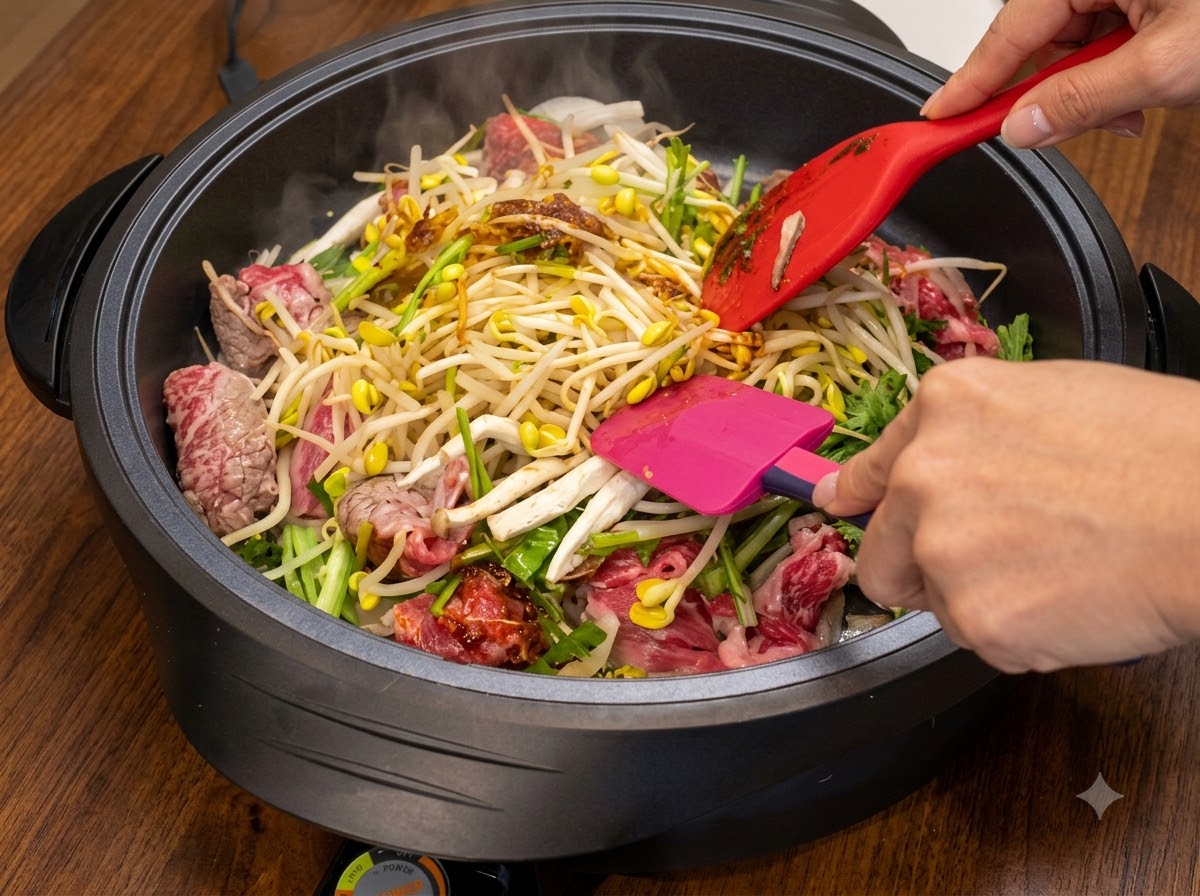 Deux spatules mélangeant les ingrédients dans une poêle chaude pendant que davantage de sauce est incorporée.