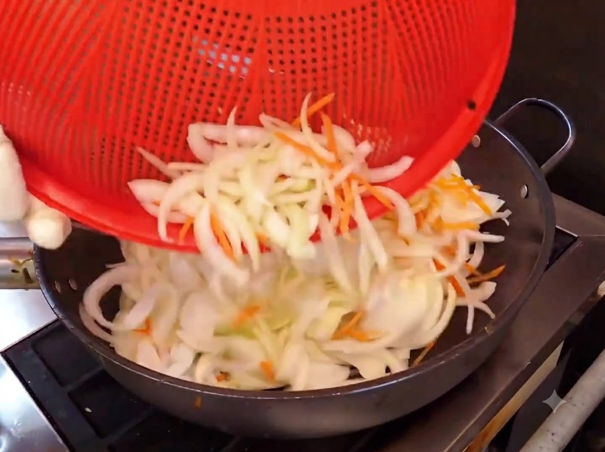 Lanières doignons et de carottes versées dun panier rouge dans un wok chaud pour être sautées.