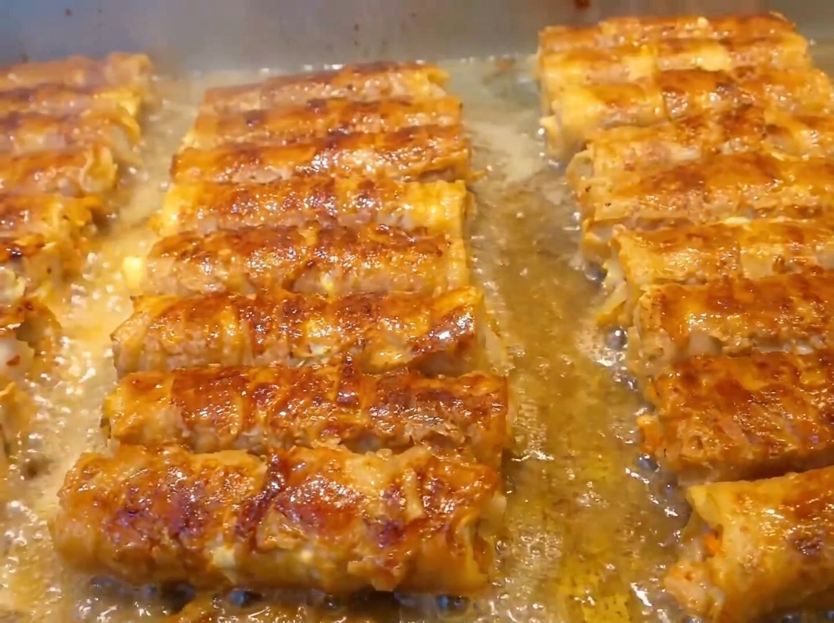 Mains roulant fermement la poitrine de porc et ses garnitures en forme cylindrique.