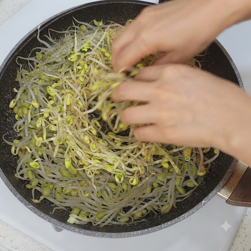 Des tranches de légumes et de poitrine de porc disposées sur des pousses de soja dans une poêle.