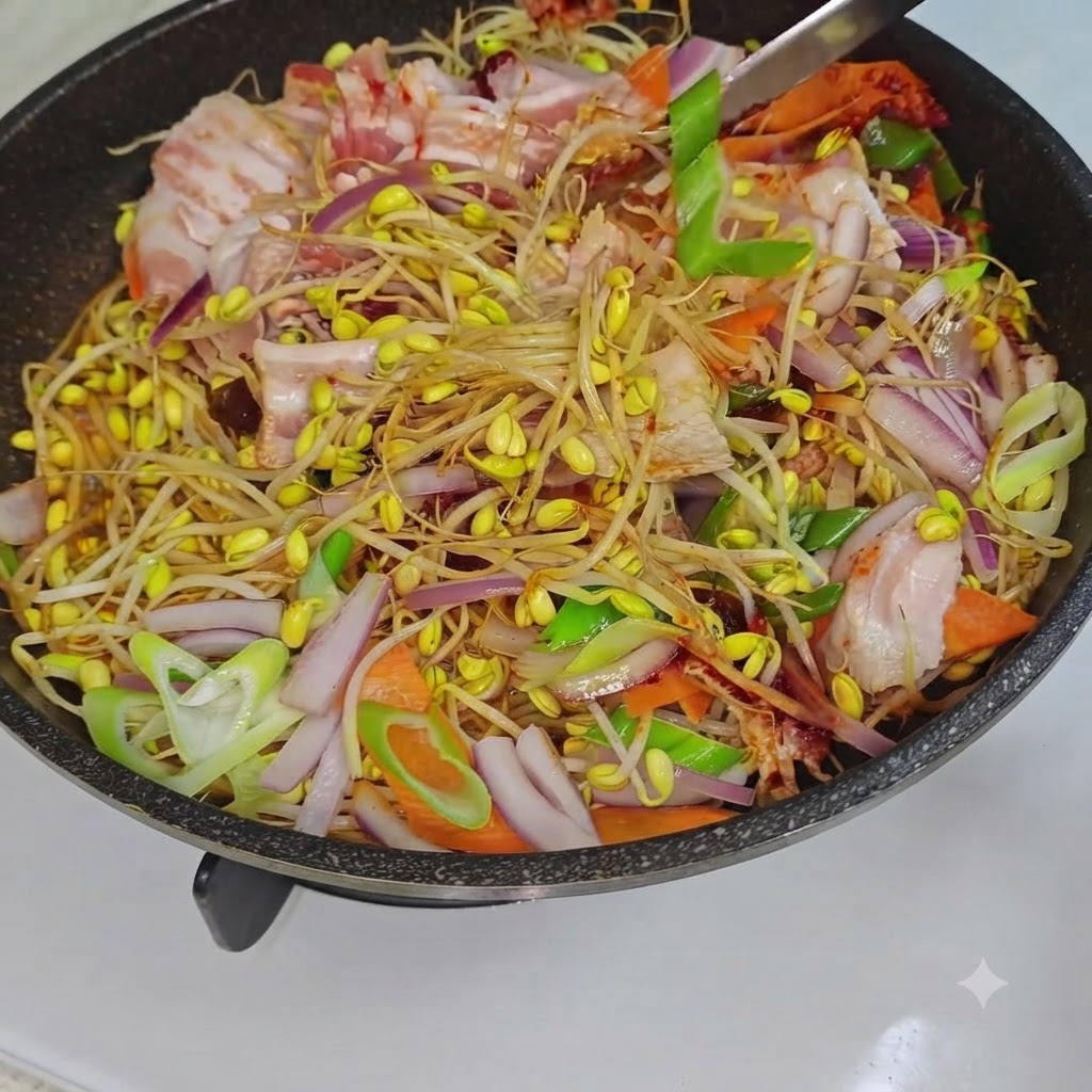 Un ustensile de cuisine mélangeant les pousses de soja, la poitrine de porc et les légumes à lintérieur dune poêle sur le feu.