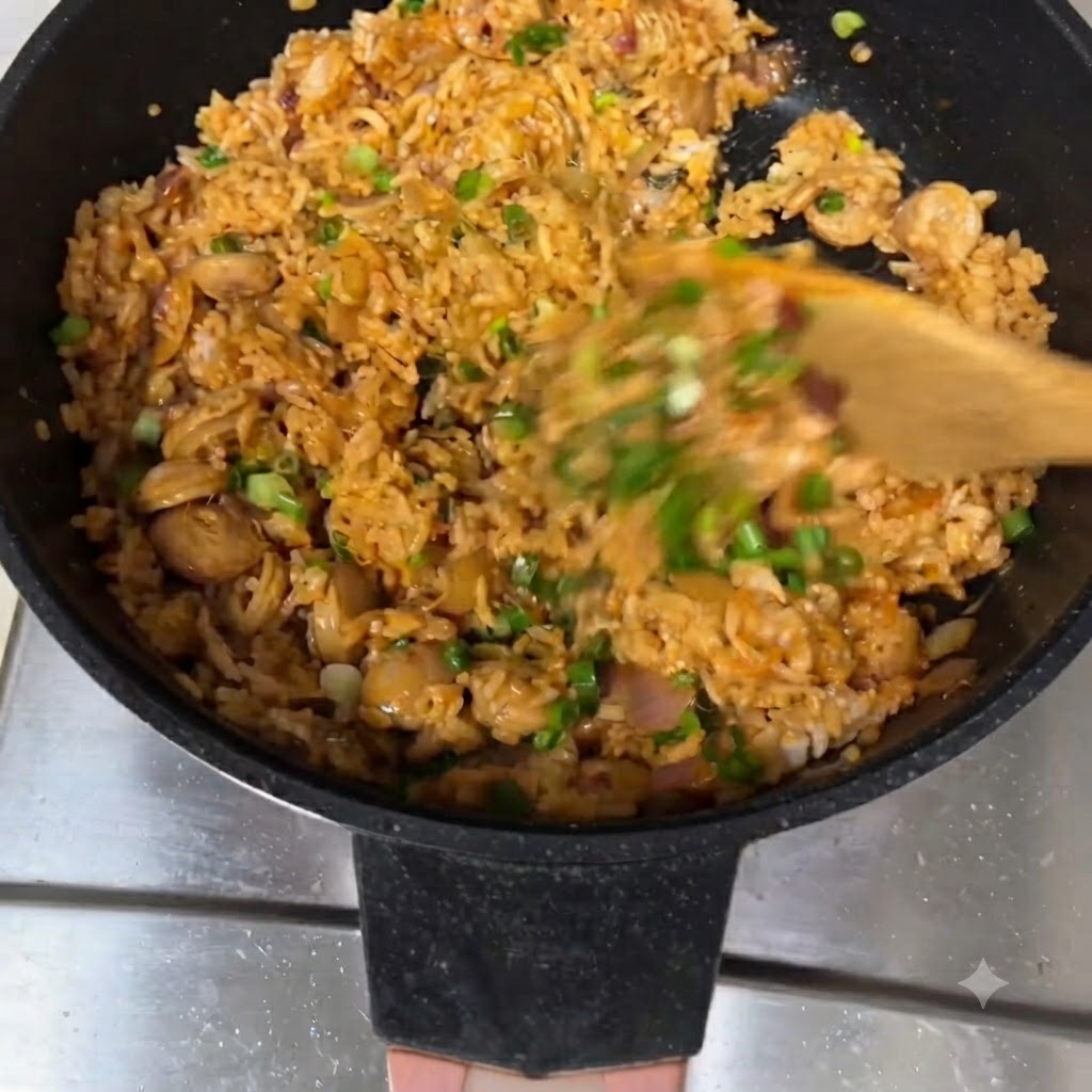 Riz frit remué avec une spatule en bois dans une poêle, garni doignons verts.