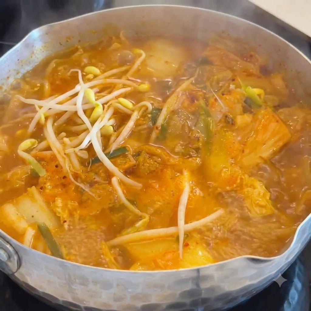 Des germes de soja blancs et croquants ajoutés dans une soupe de kimchi et de saucisses frémissante.
