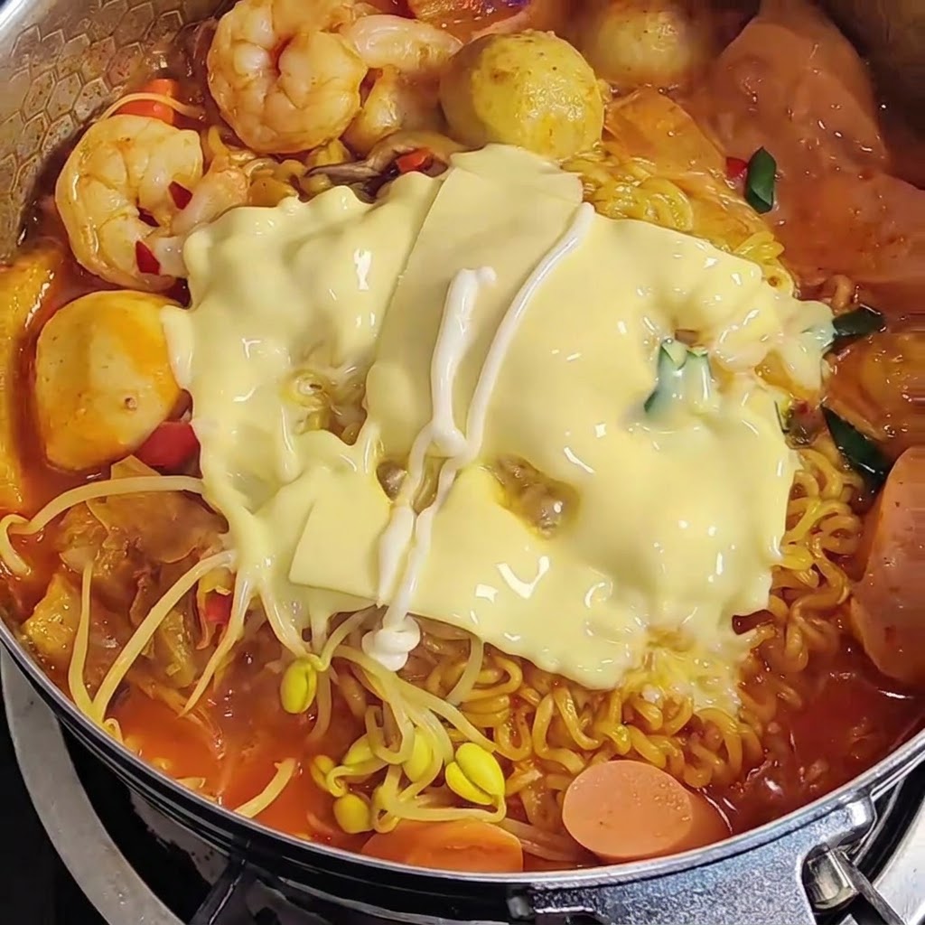 Mayonnaise versée en zigzag sur le fromage fondu recouvrant les ramen.