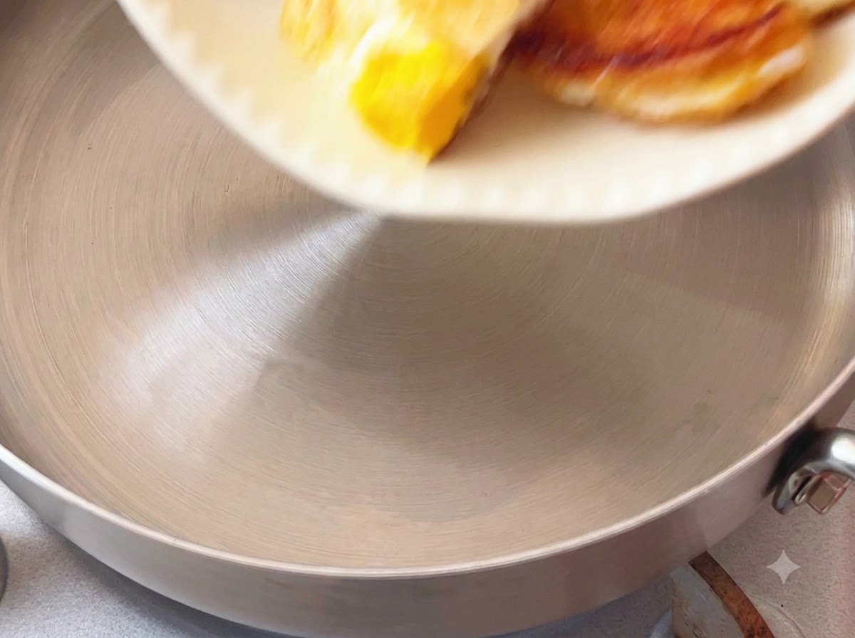 Des morceaux dœuf frit versés dans une casserole depuis un plat blanc.