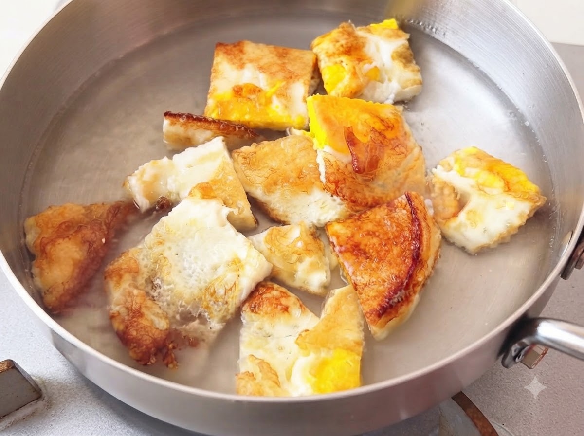 De leau chaude versée dans une casserole en métal contenant des morceaux dœuf frit.
