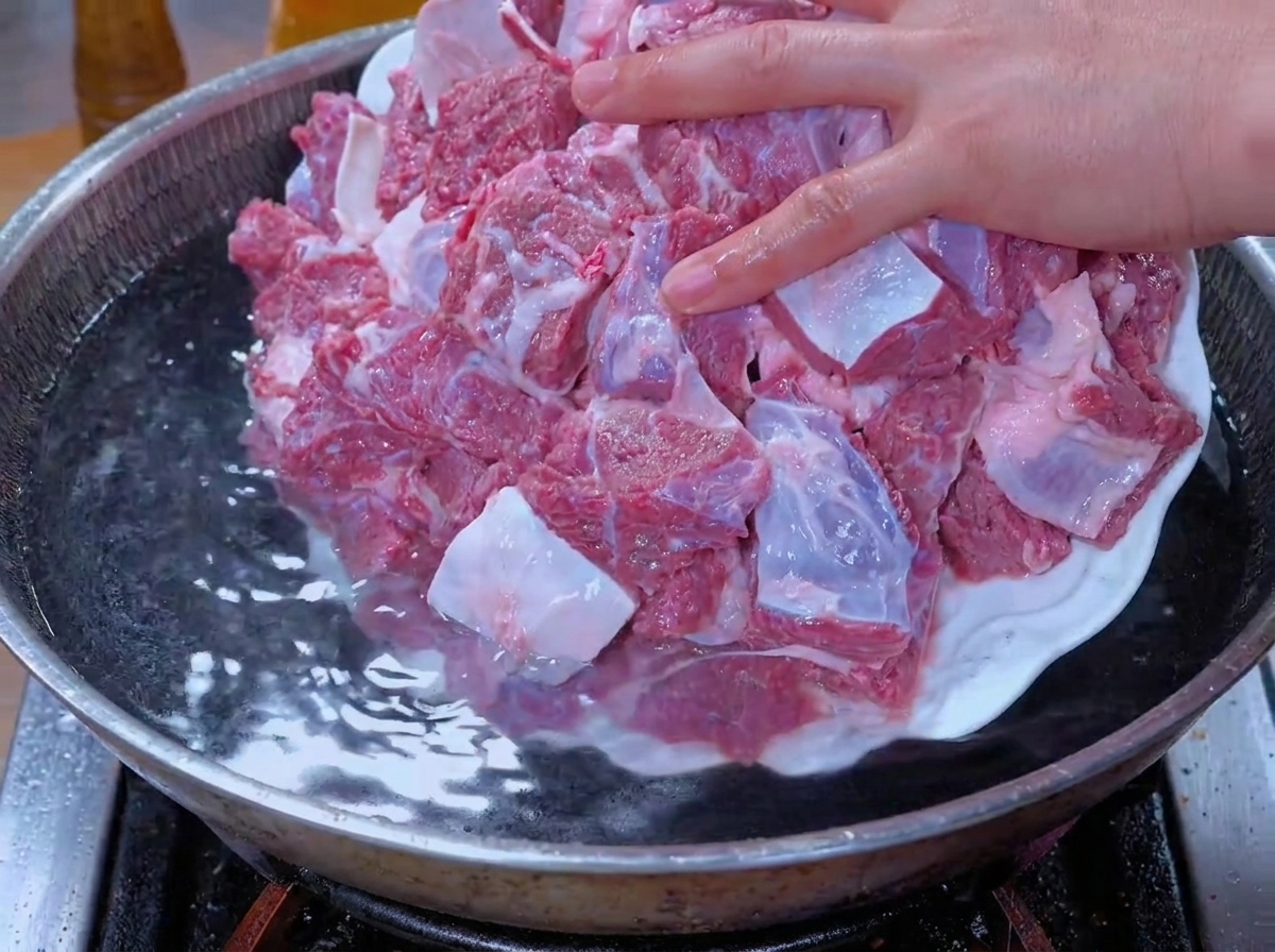 Les morceaux de bœuf égouttés sont plongés dans une marmite deau bouillante.