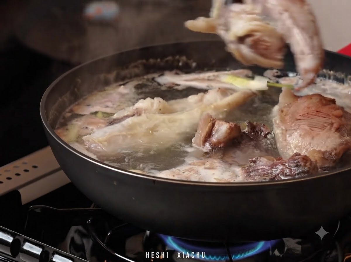 Des morceaux de gîte de bœuf transférés dans une casserole deau chaude avec du bouillon de soupe et des aromatiques.