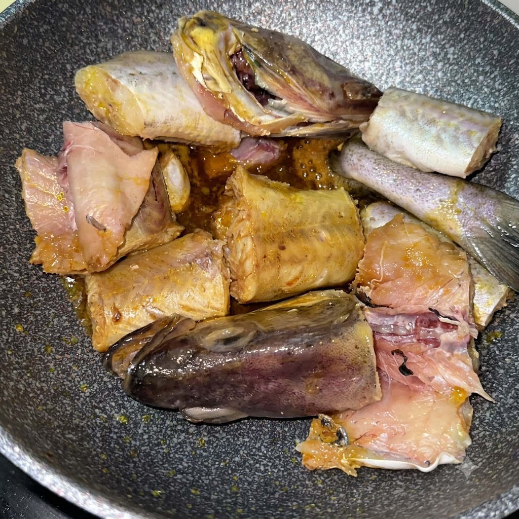 Morceaux de colin en train de saisir dans la poêle aux côtés de tranches de pommes de terre jaunes.
