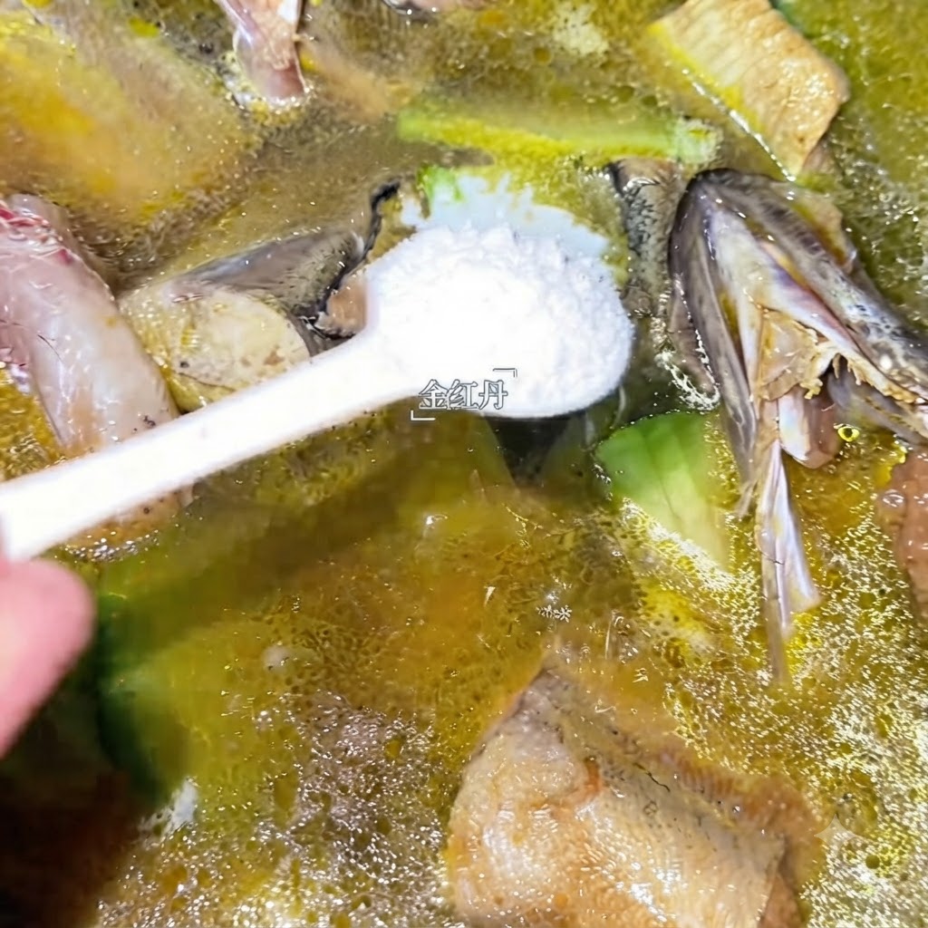 Une cuillère de condiment blanc en train dêtre ajoutée dans la cocotte frémissante de soupe de colin.