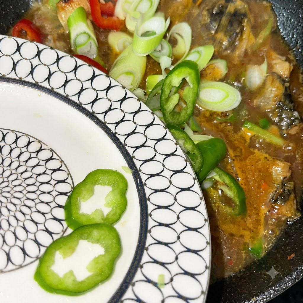 Oignons verts fraîchement tranchés ainsi que des piments rouges et verts versés depuis une assiette blanche à motifs dans la marmite frémissante.