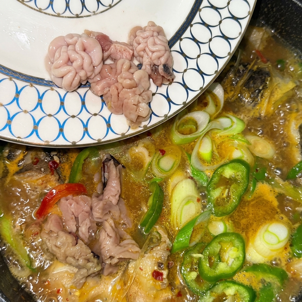 Laitance et œufs de poisson frais transférés dune assiette à motifs directement dans la soupe bouillante.