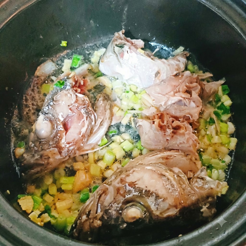 Morceaux de poisson colin et tête en train de frire dans une casserole avec des aromates hachés.