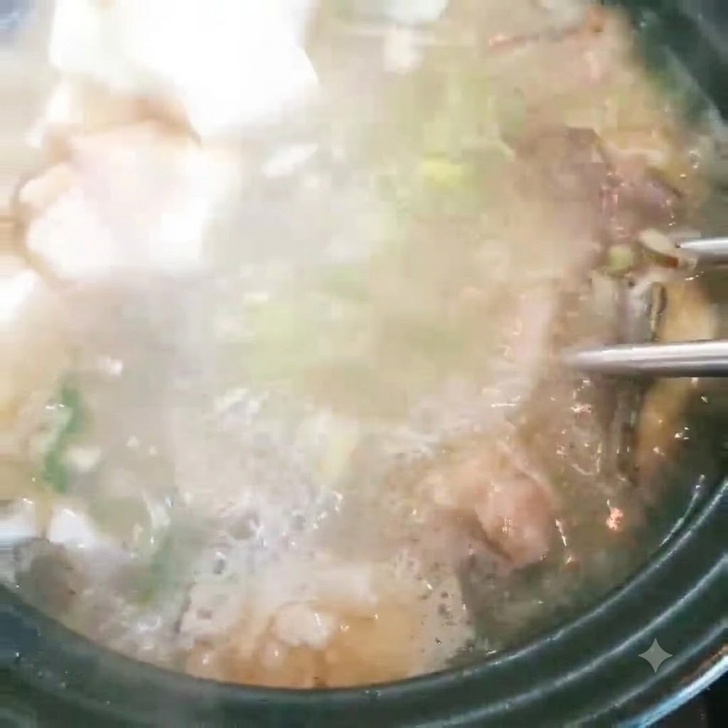 Cubes de tofu ajoutés à une casserole de soupe de poisson bouillonnante avec des oignons verts.