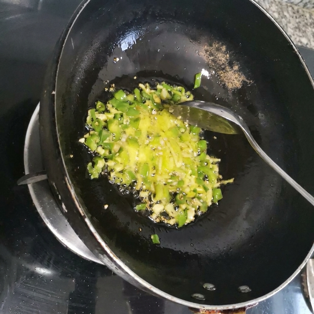 Piment rouge émincé en train dêtre sauté avec les aromates verts à lintérieur dun wok sombre.