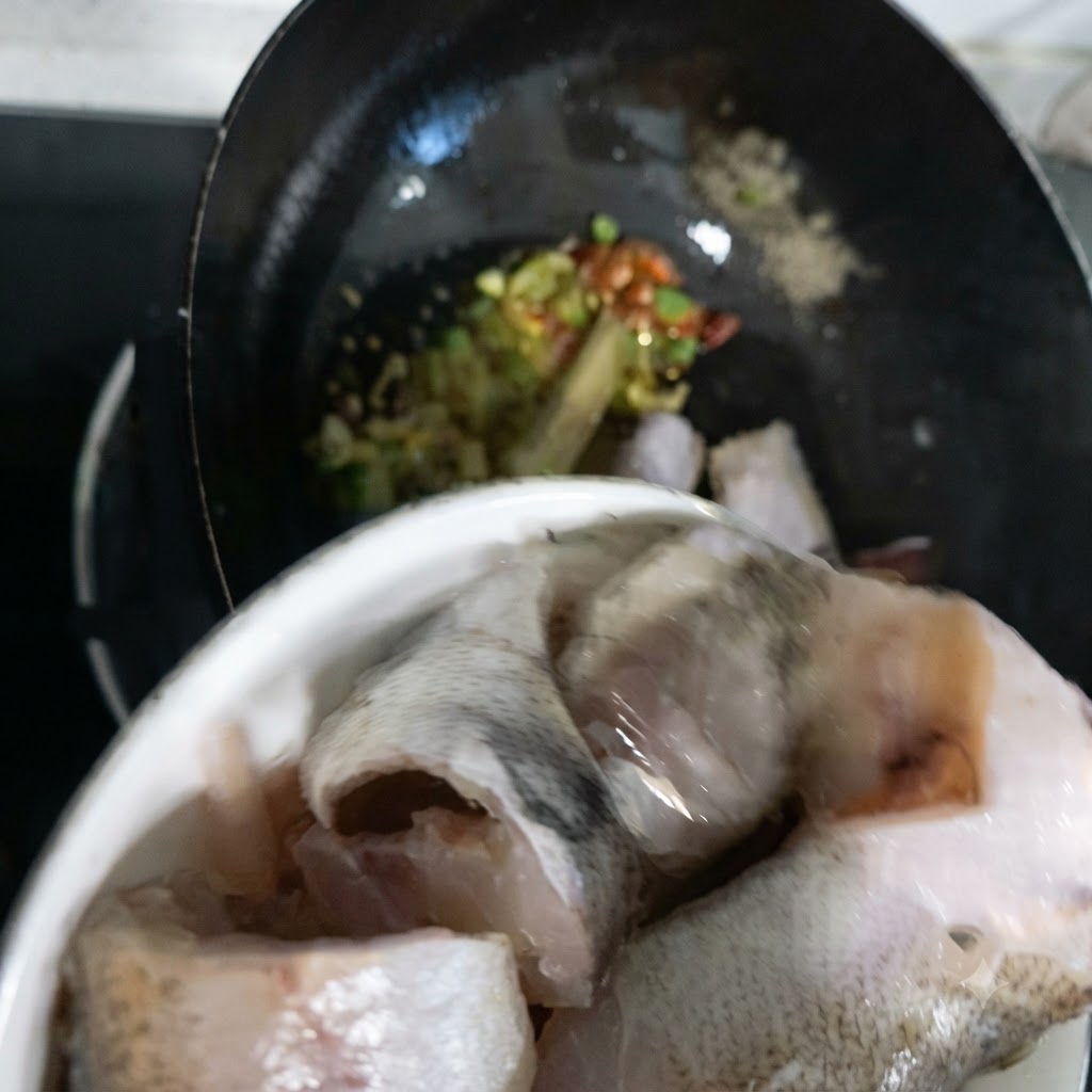 Morceaux de poisson lieu en train dêtre transférés dun bol dans le wok.