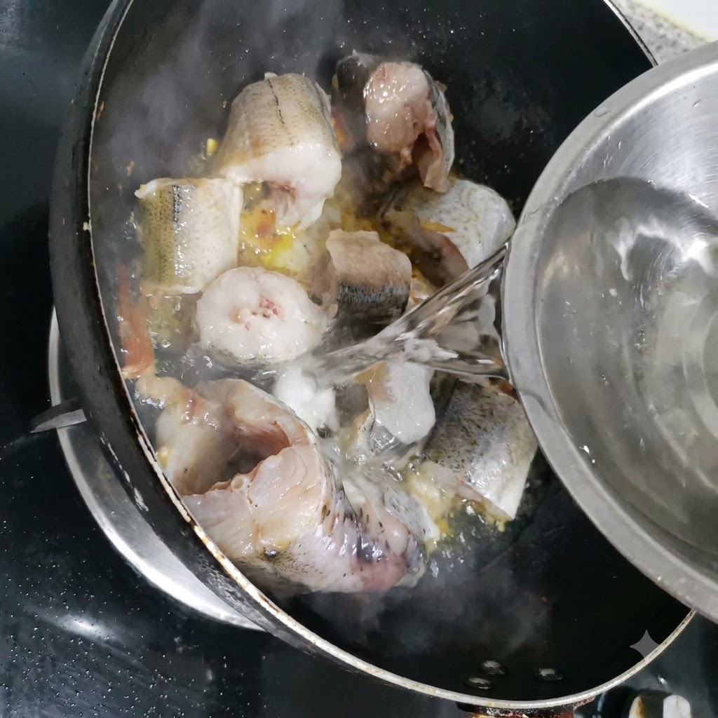 De leau étant versée dun bol en métal dans la poêle avec les morceaux de lieu.