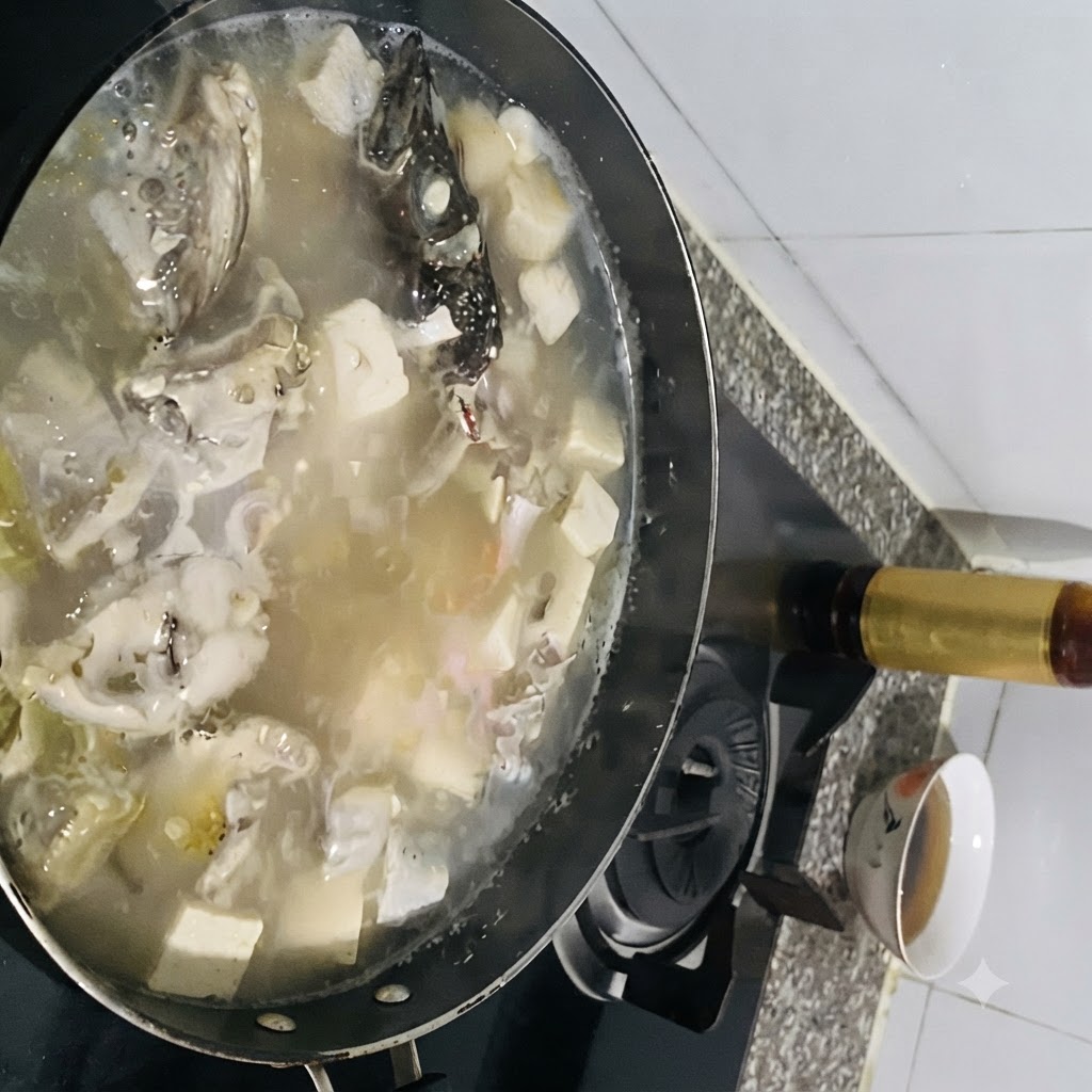 Des assaisonnements ajoutés à une casserole bouillante de soupe de poisson au tofu.