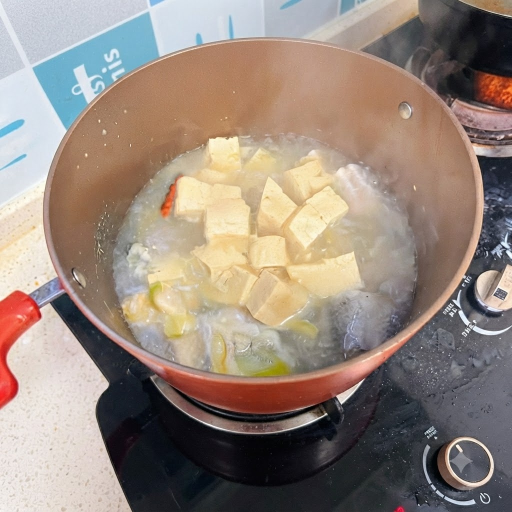 Une marmite de soupe de poisson et de tofu mijotant sur le feu avec un bouillon blanc laiteux.