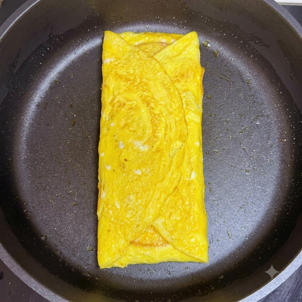 Une tranche de jambon rose pliée superposée au fromage à lintérieur du wrap dœufs cuits dans la poêle.